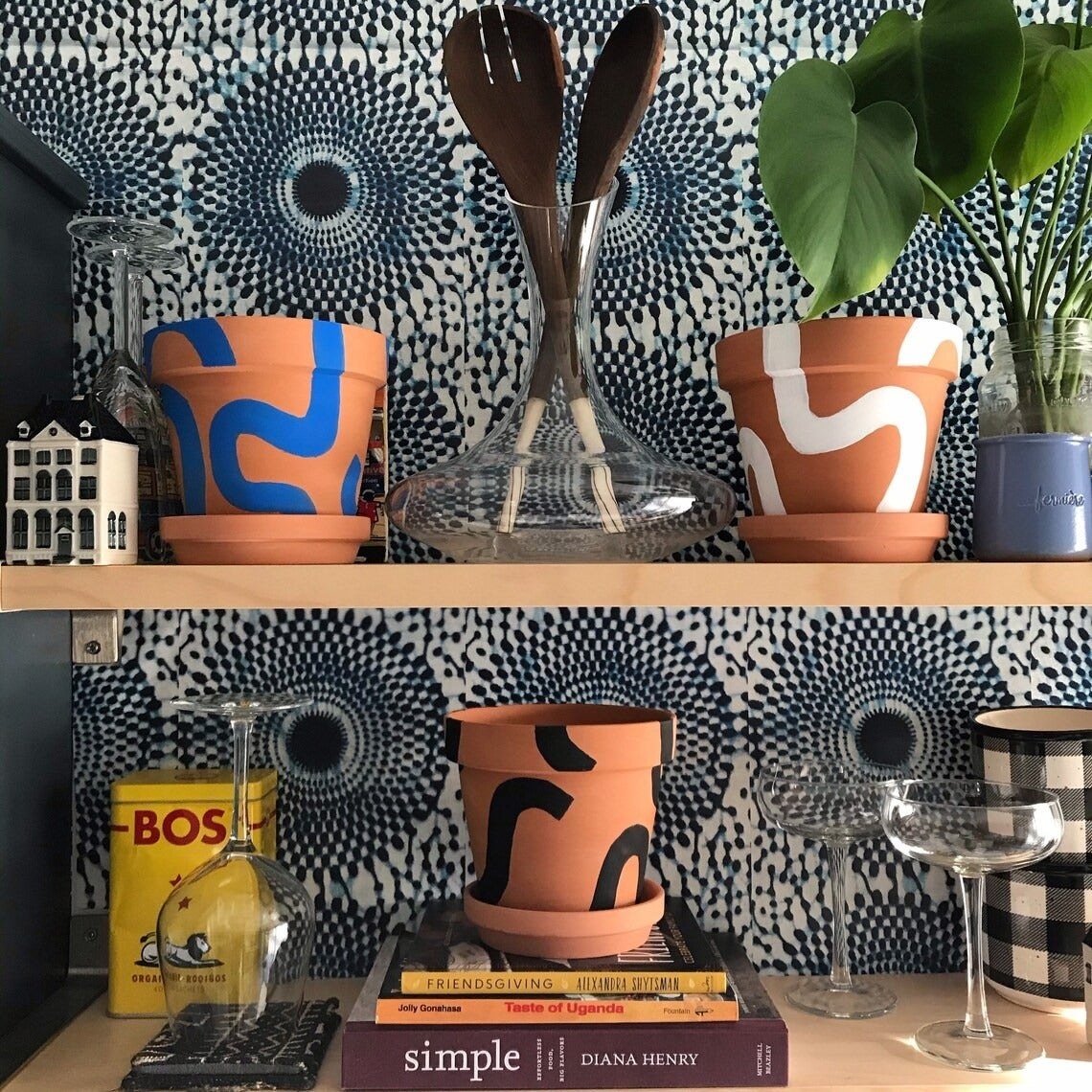 three plant pots sitting on a two kitchen shelves