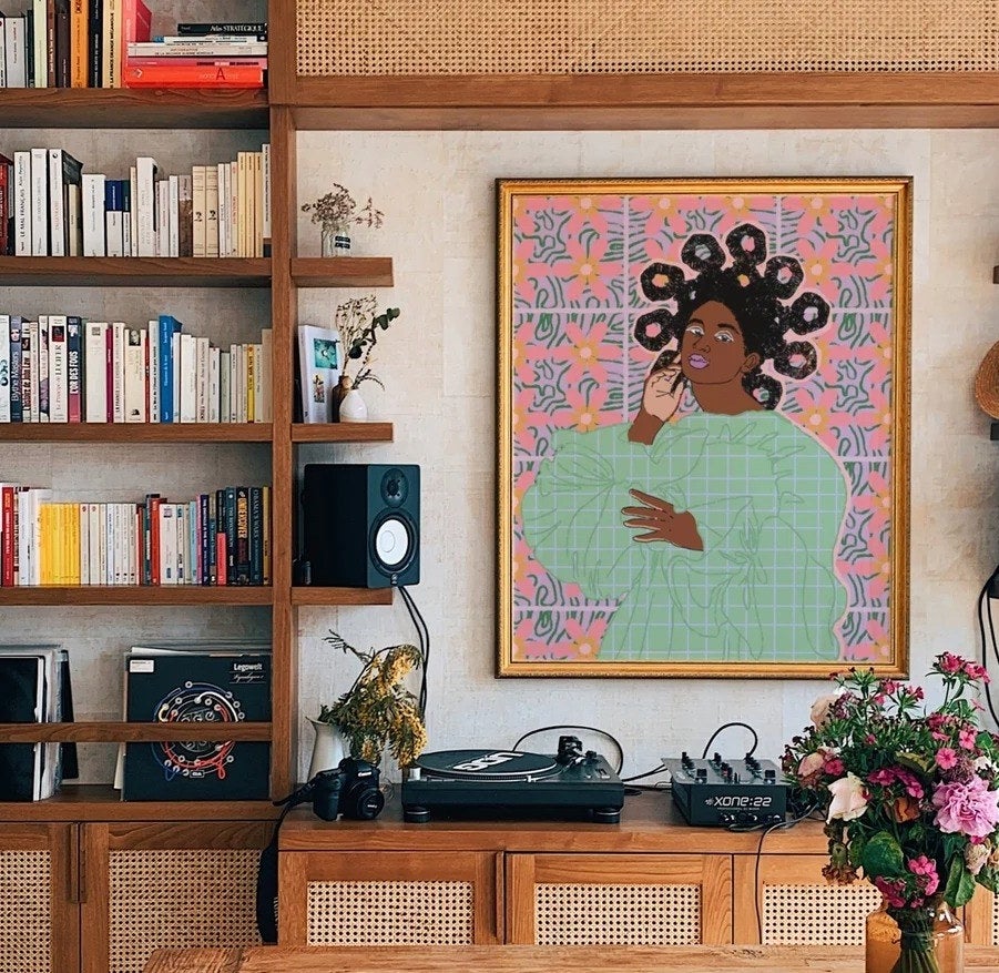 a colorful art print hanging above a record player and bookshelves
