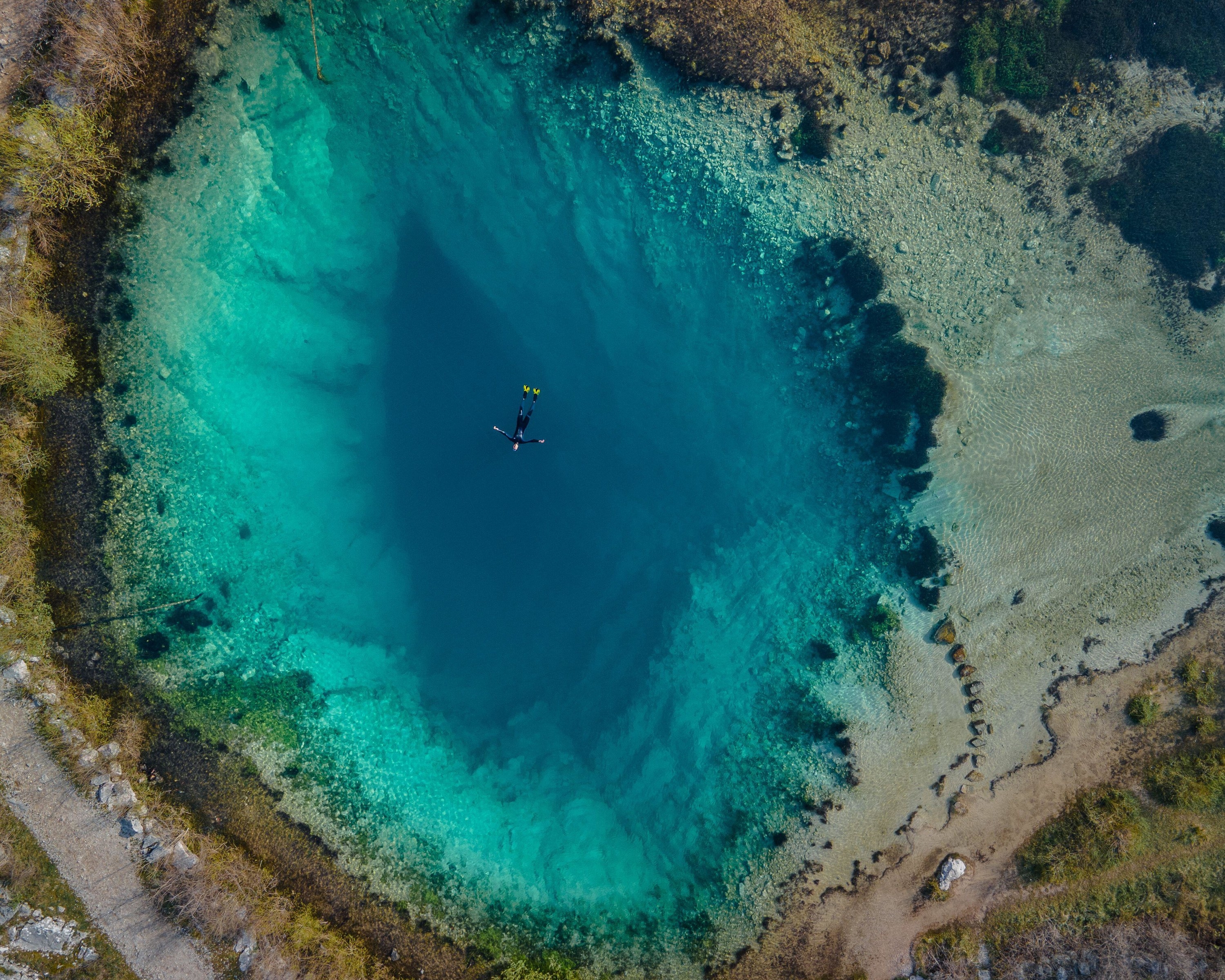 A diver floating on top of a huge blue hole of water