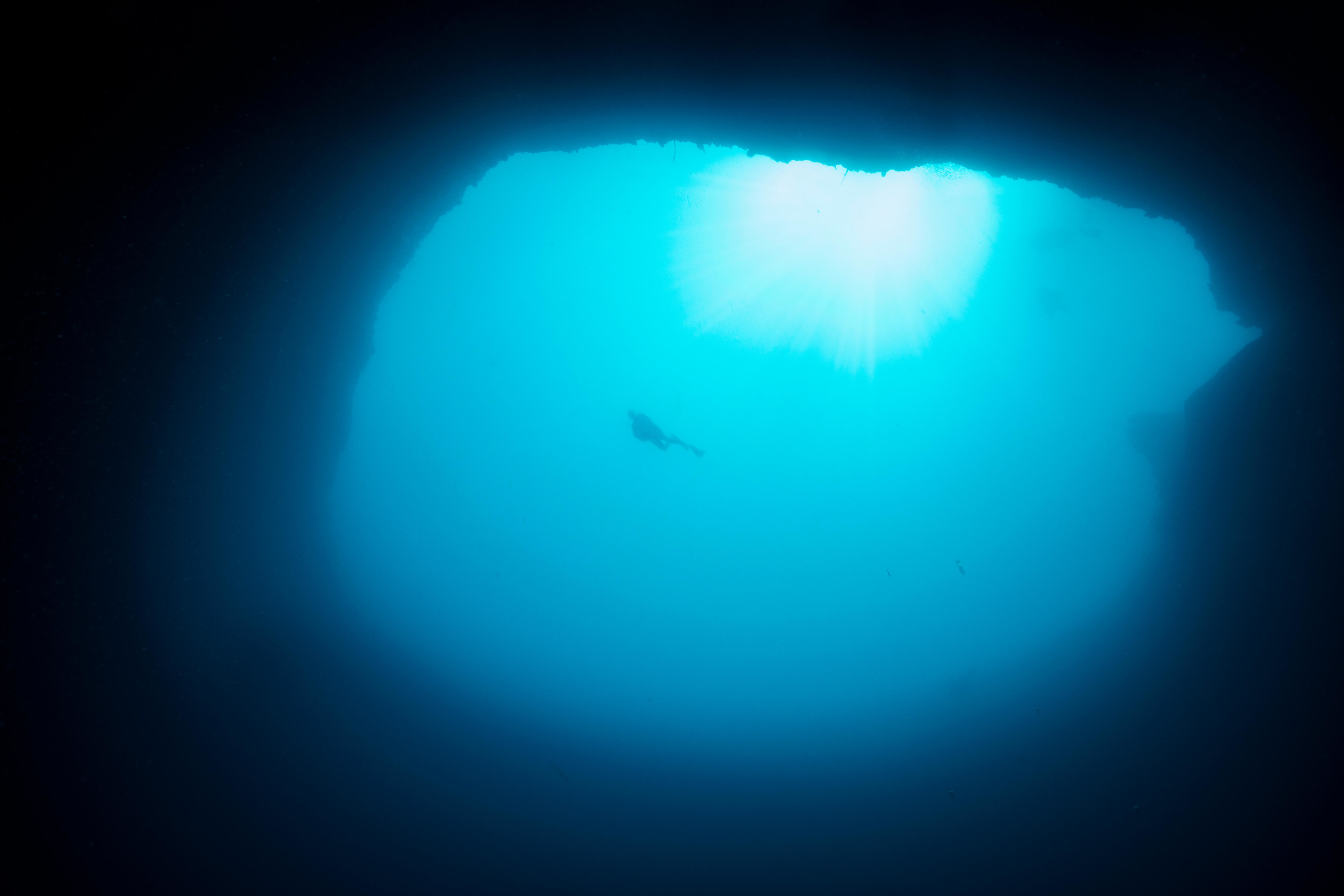 A huge hole with bluish light of different shades, with a diver visible