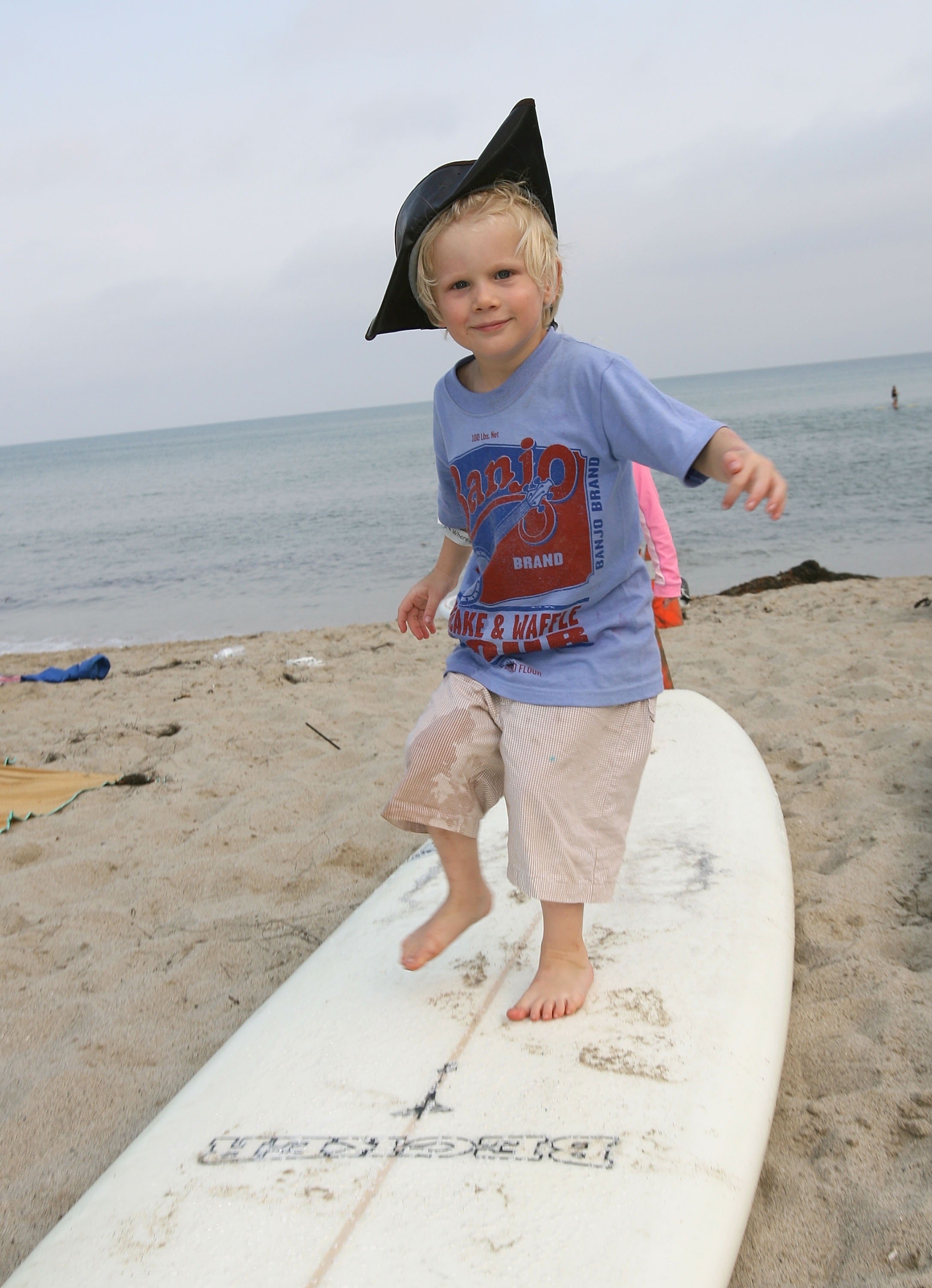 Banjo Taylor as a child standing on a surfboard in 2007