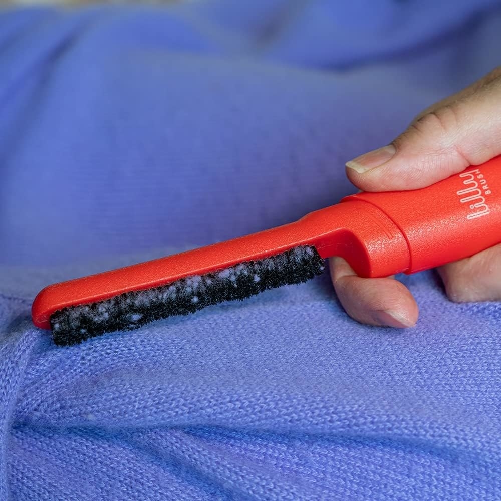 a person using the brush to de-lint a sweater