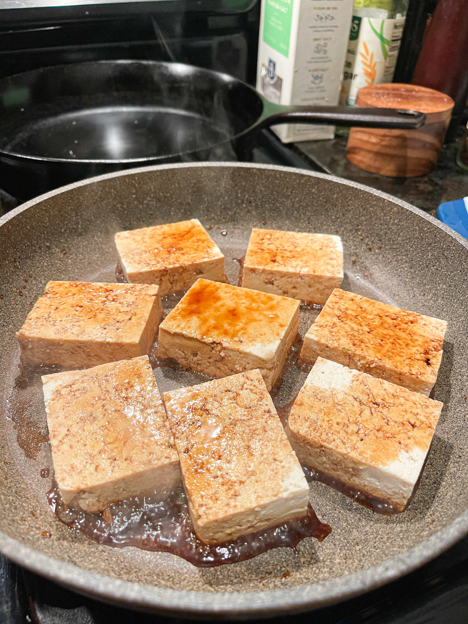 tofu cooking in dry skillet with soy sauce poured overtop and around