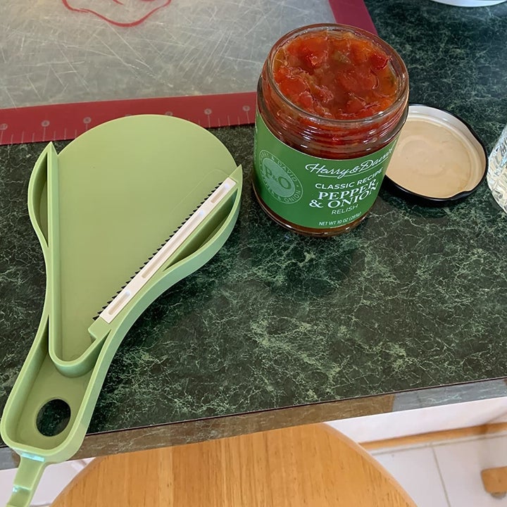 upside down view of the teeth of the opener sat beside an open jar of salsa