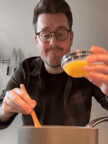 author whisking beaten egg into saucepan