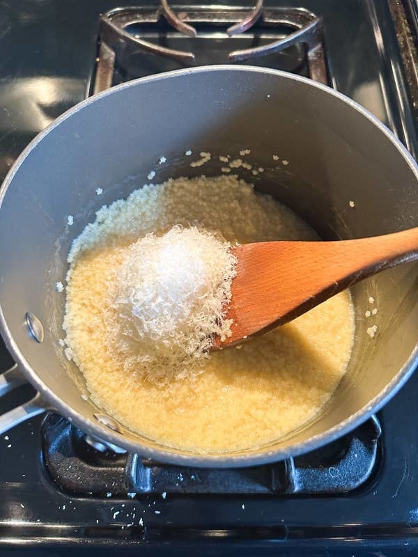 author stirring parmesan cheese into saucepan of pastina