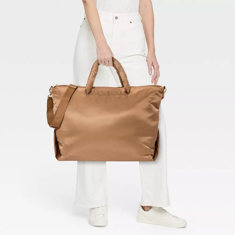 a model carrying the satiny caramel colored bag