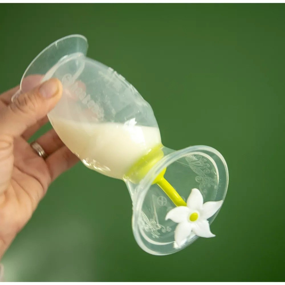 a hand holding the breast pump with milk in it