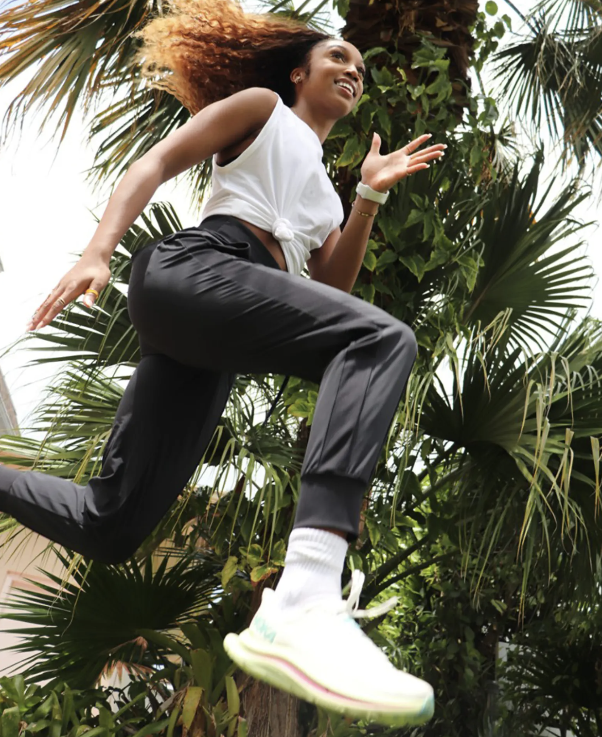 A person jogging under palm trees while wearing the joggers