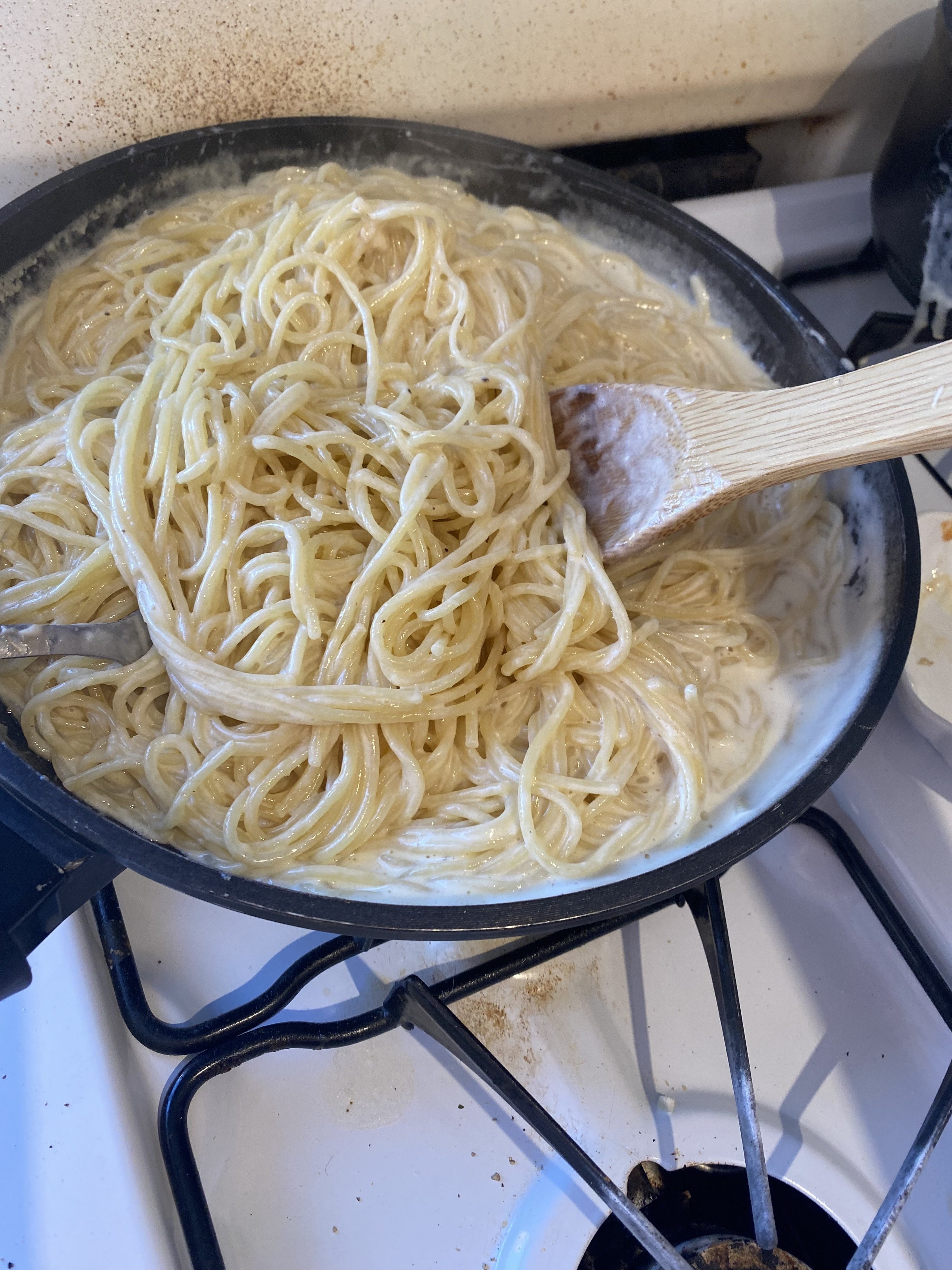 the noodles being added to the pan with the sauce