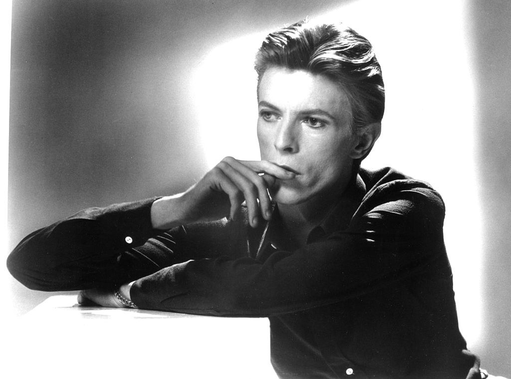 Bowie with his arms folded and his finger to his lips