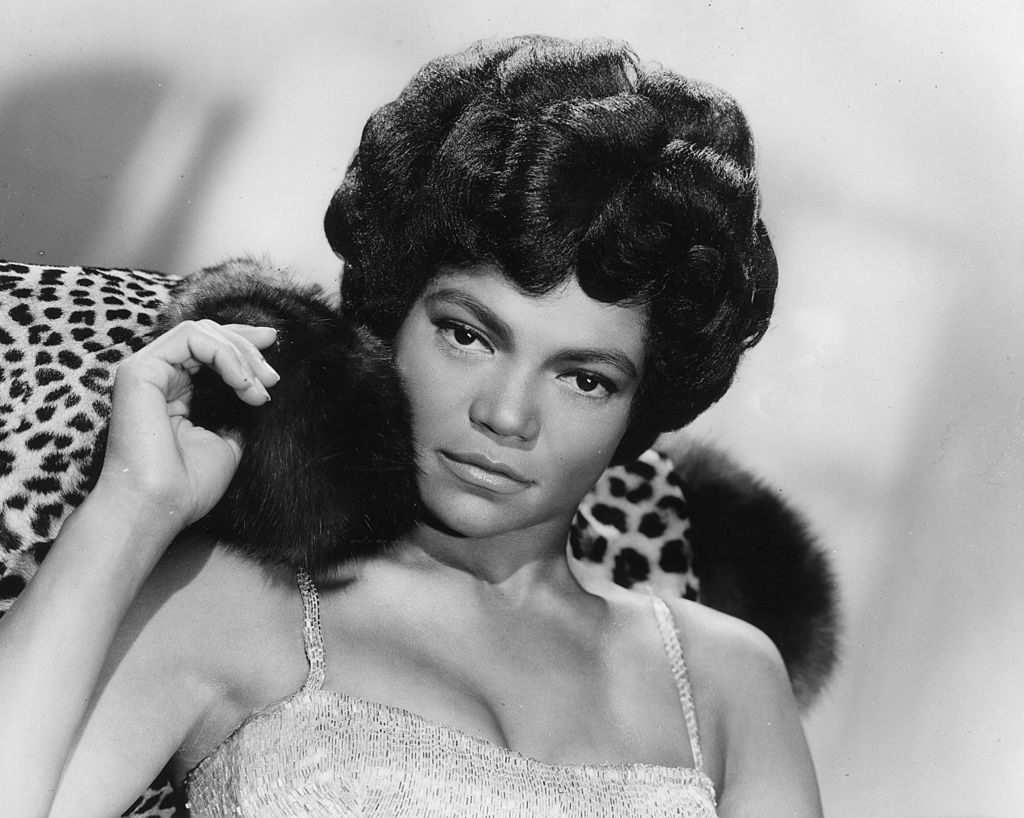 Close-up of Eartha in a spaghetti-strap outfit with an animal-print coat behind her
