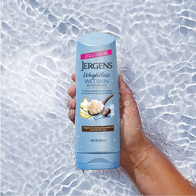 A person holding a bottle of in-shower lotion in water