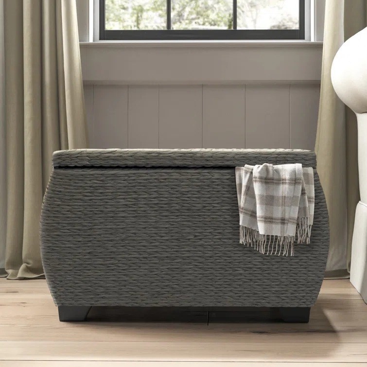 the storage trunk in gray with a blanket hanging out of it