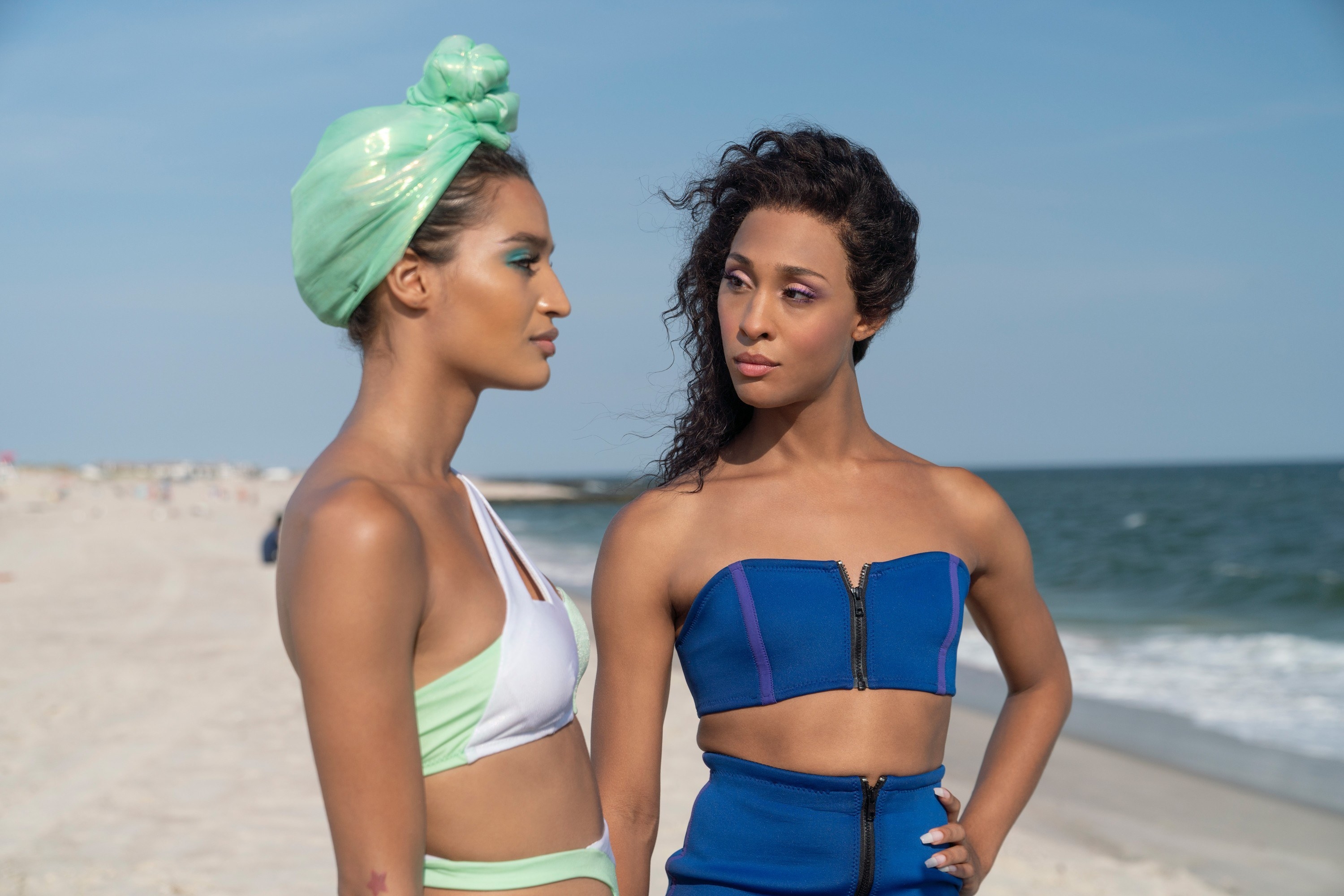 Indya Moore and Michaela Jae Rodriguez stand on a beach