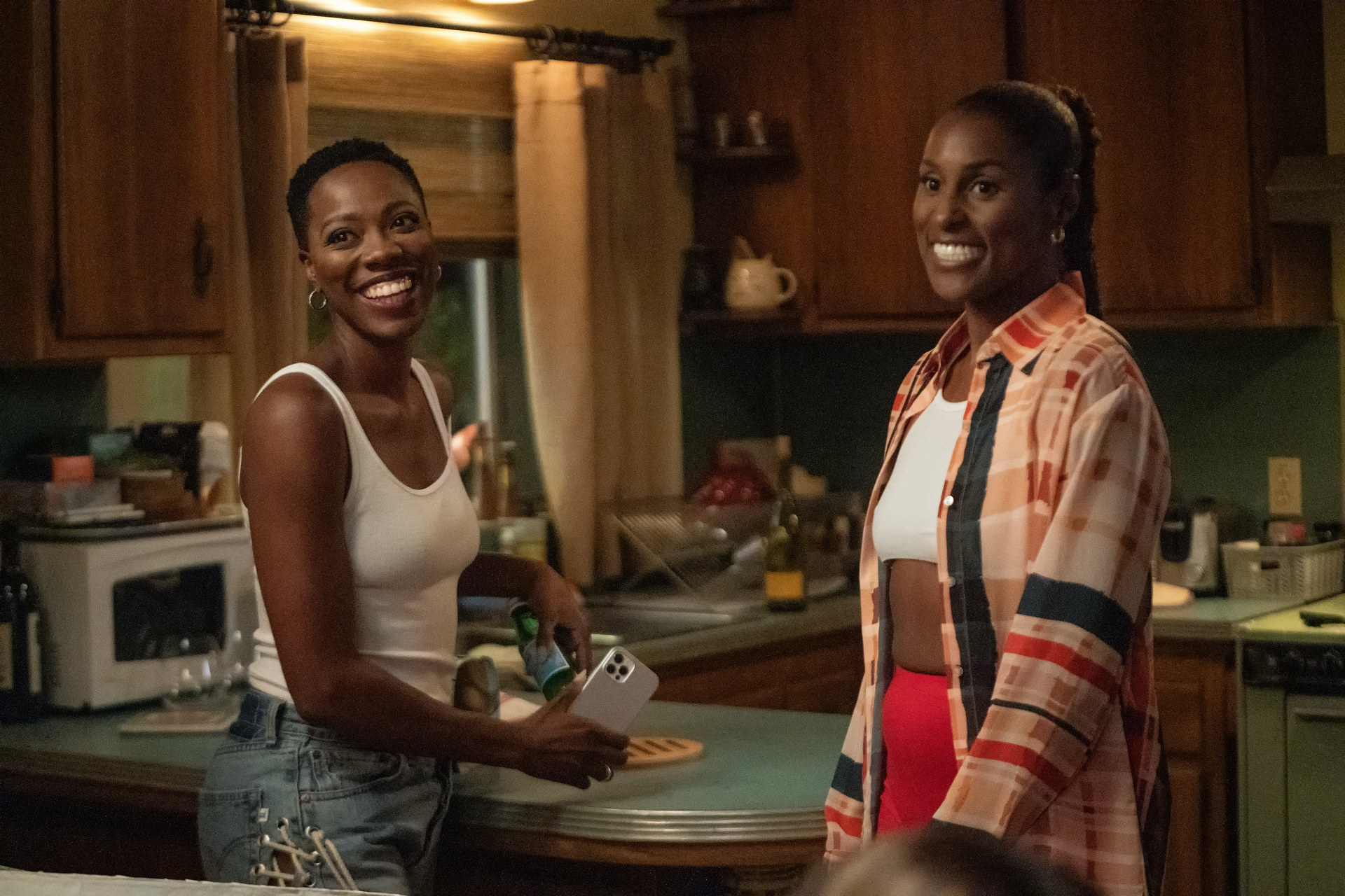 Issa Rae and Yvonne Orji stand in a kitchen