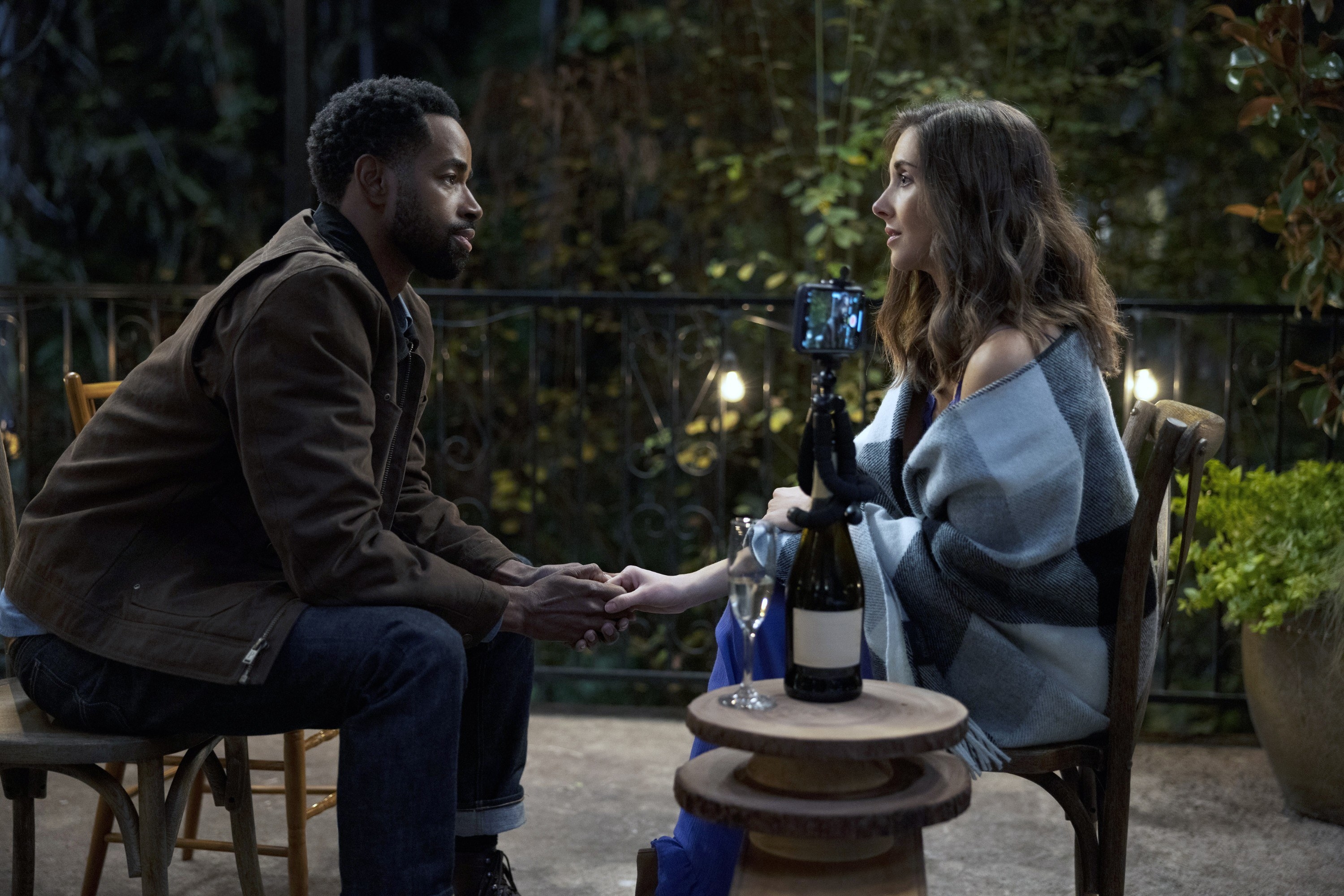 Sean and Allie holding hands and looking at each other while seated