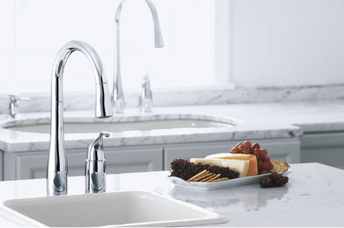 A silver faucet about a sink next to a plate of cheese