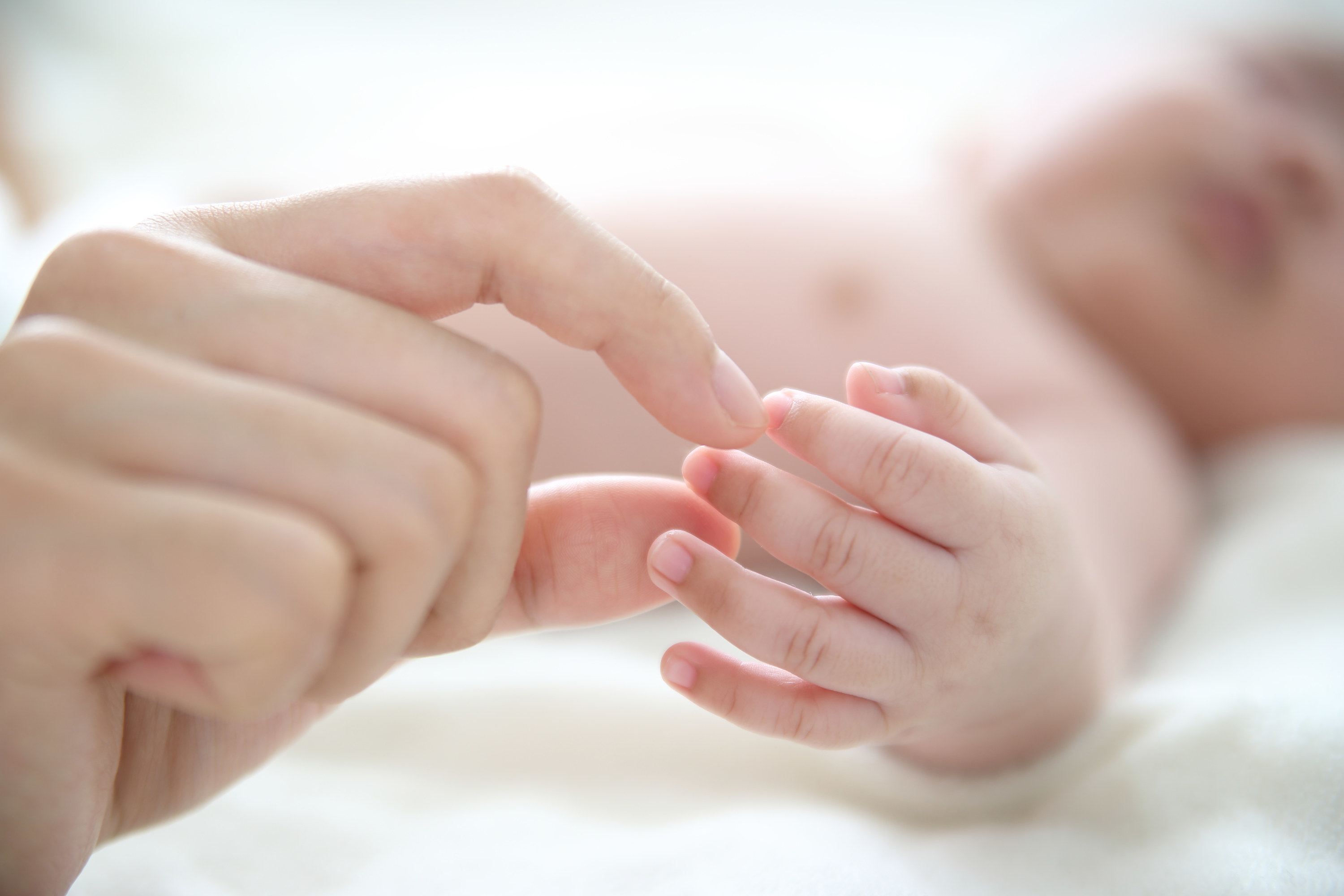 A baby has their hand held by adult