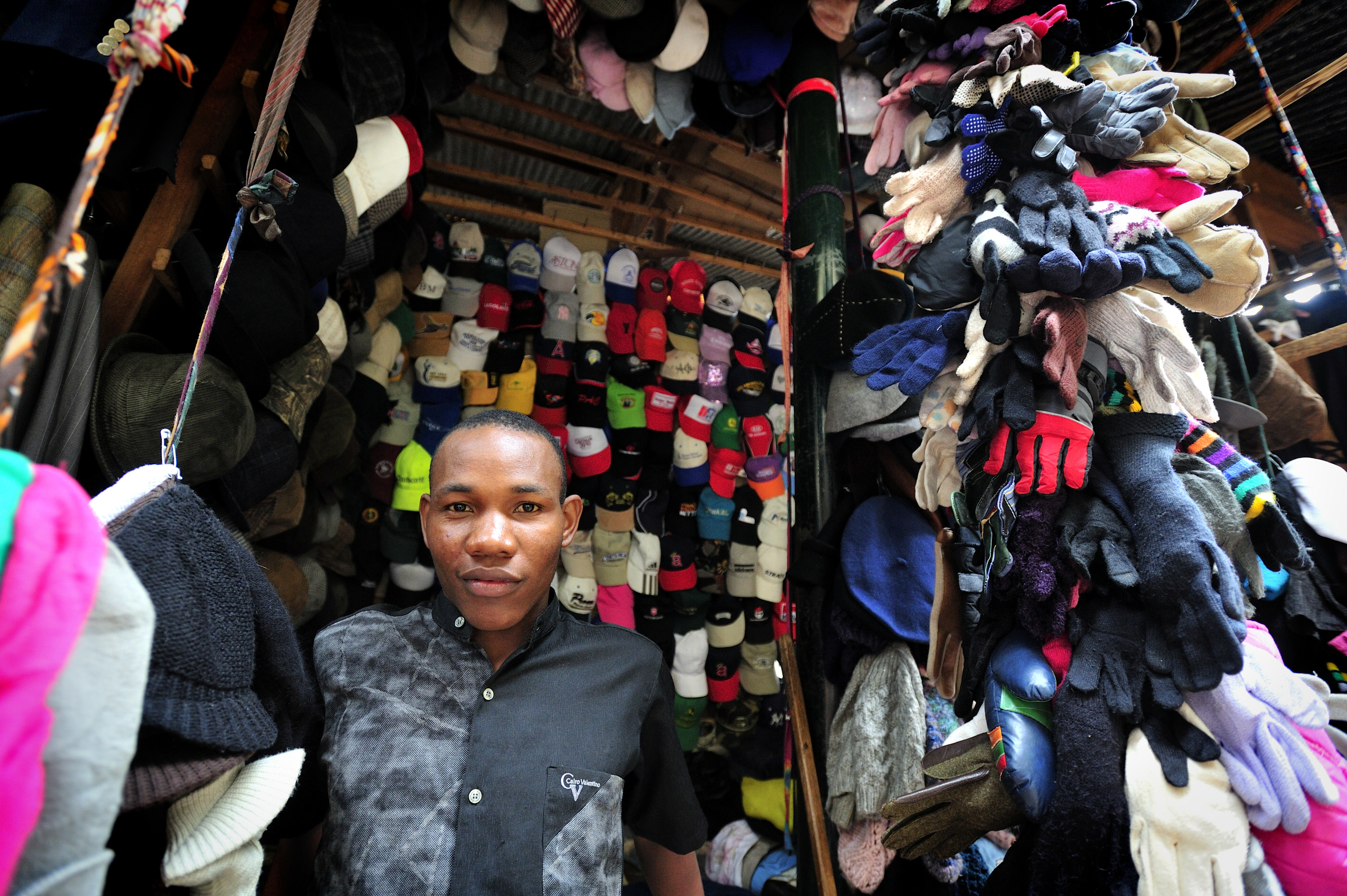 Ugandan shopkeep stands with his store items