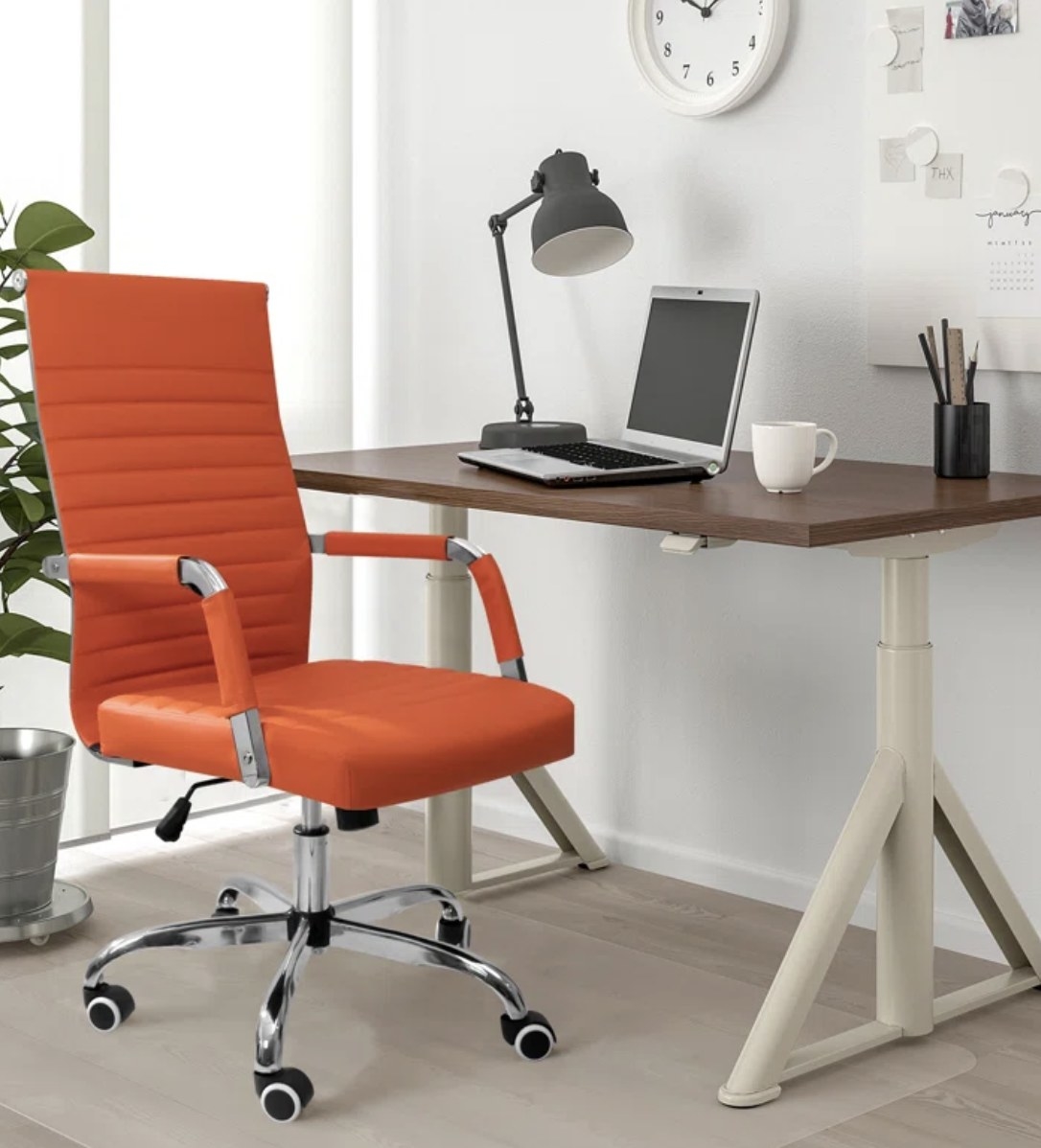 An orange desk chair on wheels in front of a desk