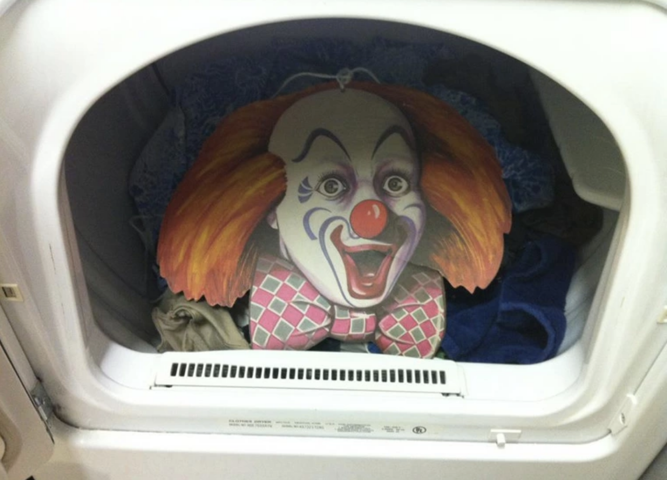 A large clown head was put on top of the pile of clothes in the dryer to scare the person who opened the drier