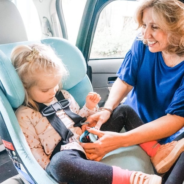 a person uses the UnbuckleMe tool to get a child out of a car seat