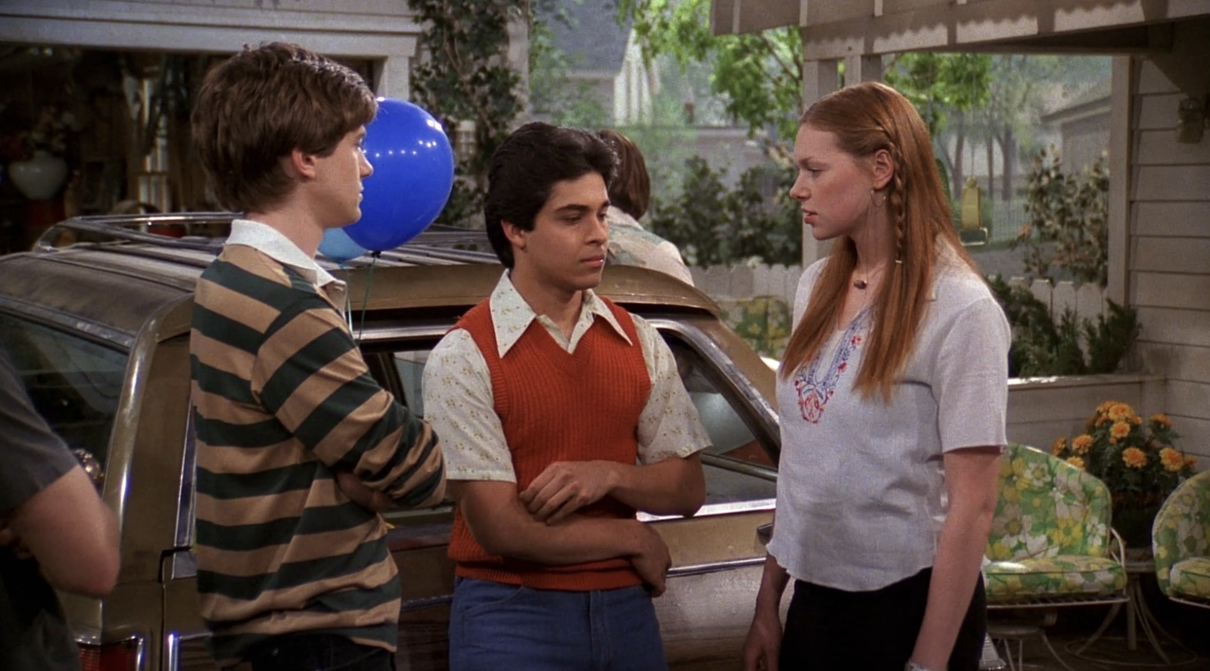 Eric and Donna look upset as Fez stands between them, holding a balloon