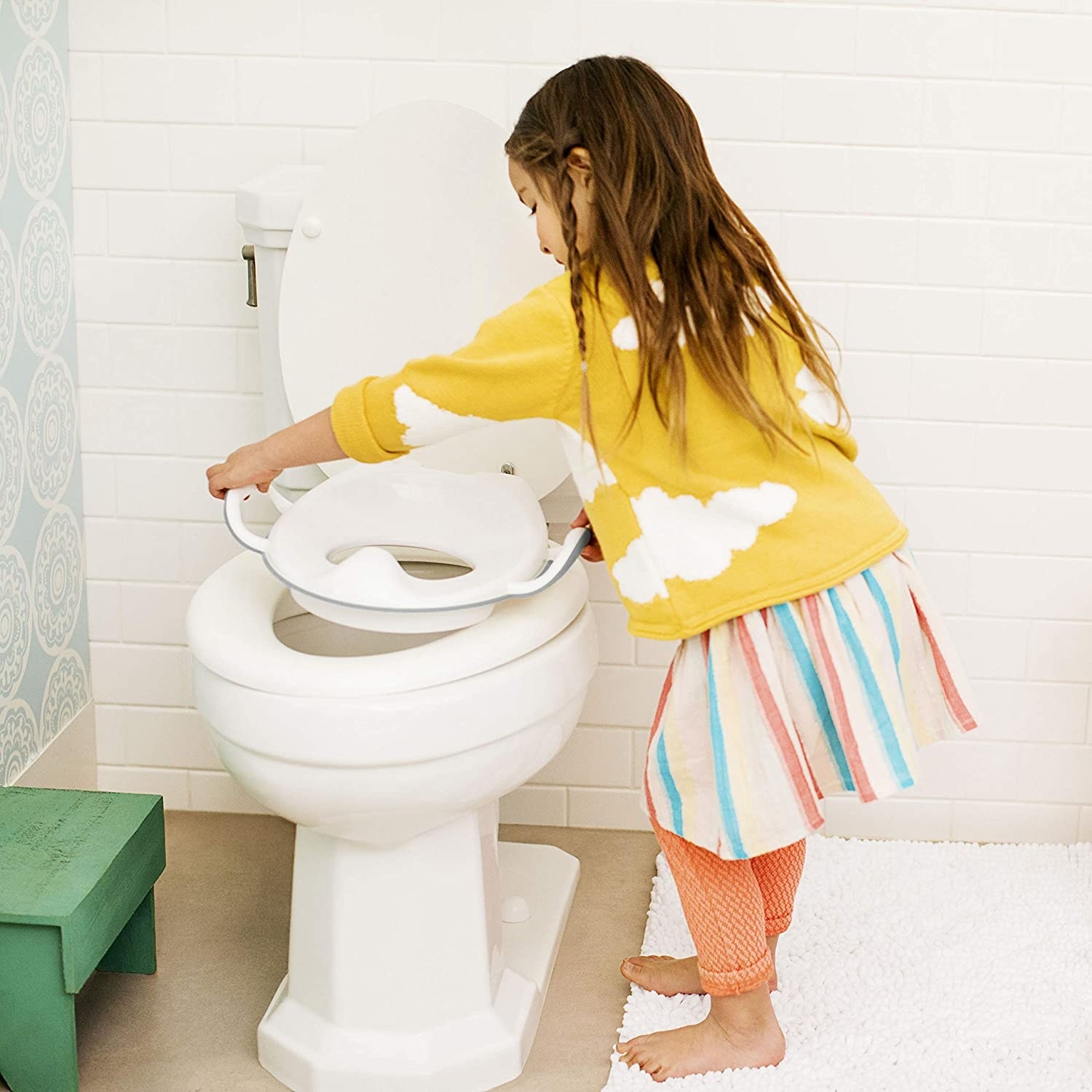 A kid placing the potty seat on the potty