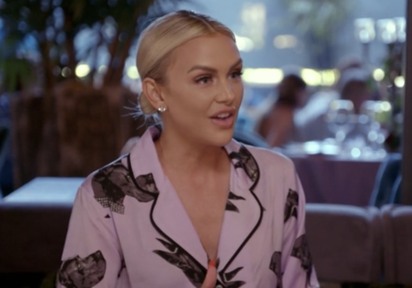 A close up of Lala talking in a bar, she&#x27;s wearing pink satin pyjamas with dog faces on them