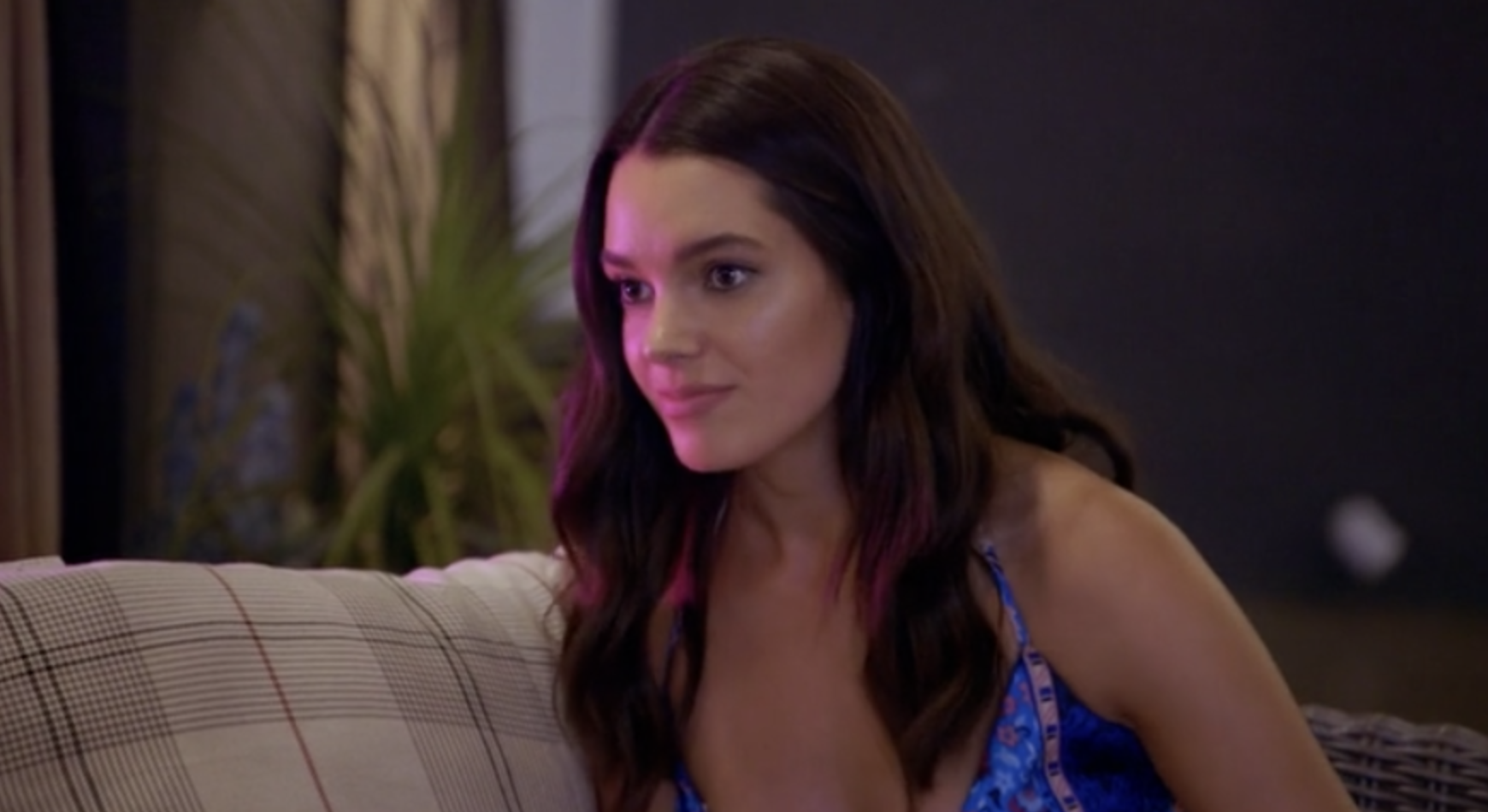 A brunette girl (Ally) sits on a couch in a bar looking at someone