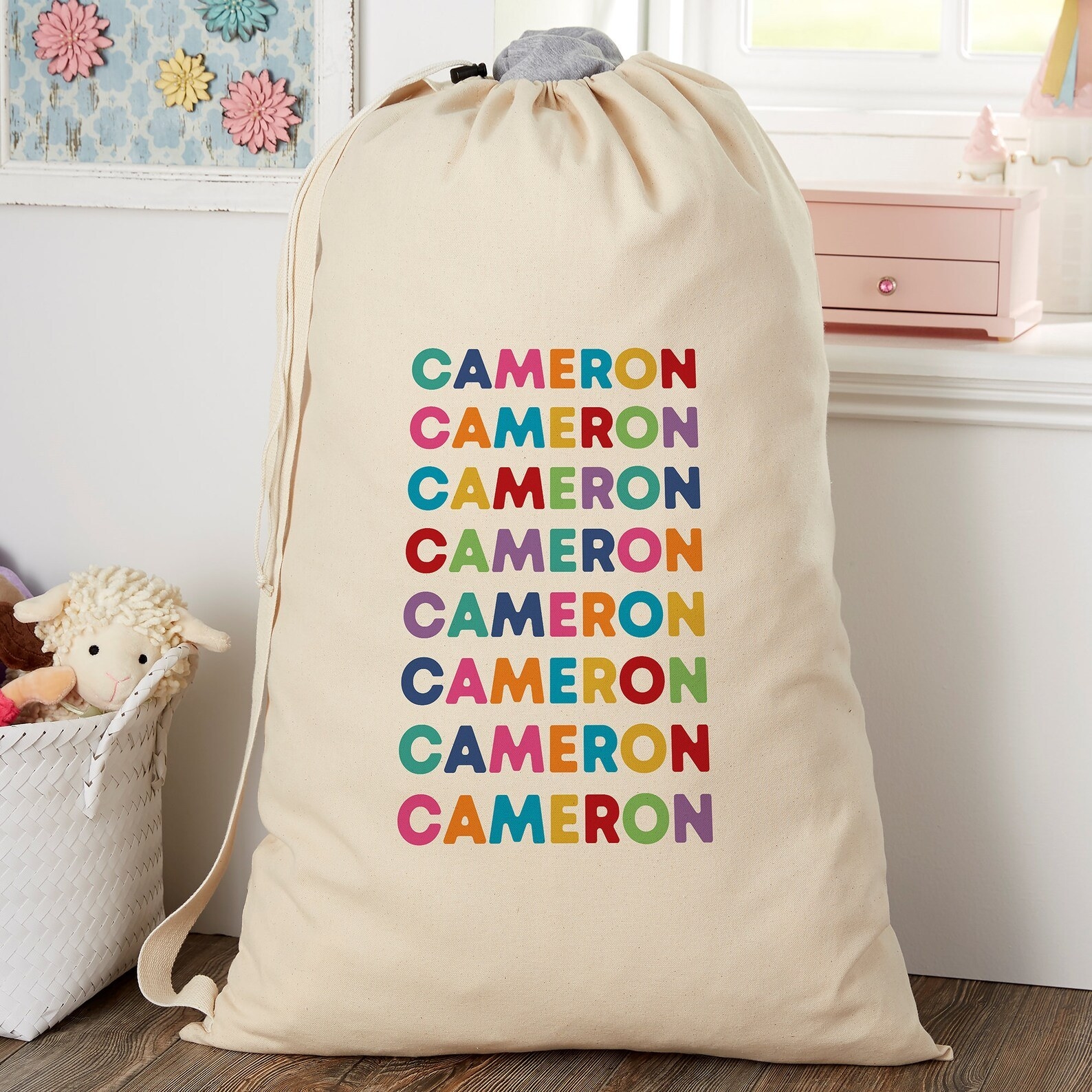 Light canvas colored laundry bag with repeating rainbow letters spelling child&#x27;s name