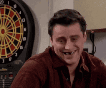A GIF of Joey from Friends smiling with food stuck in his teeth