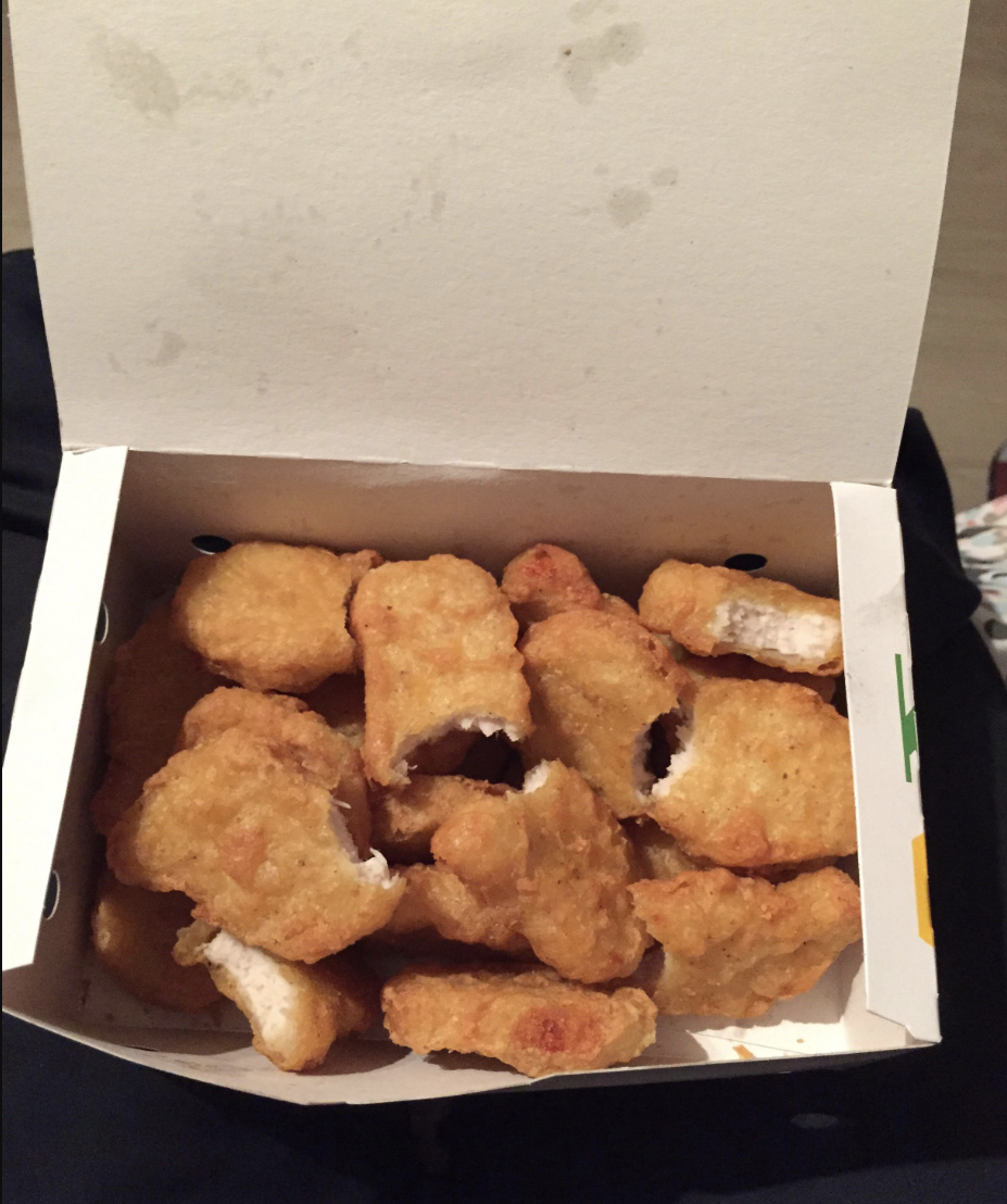 A box of chicken nuggets in which all of the nuggets have one bite taken out of them