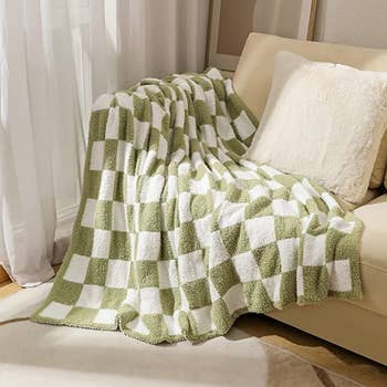 a green and white checkered throw blanket tossed on a couch