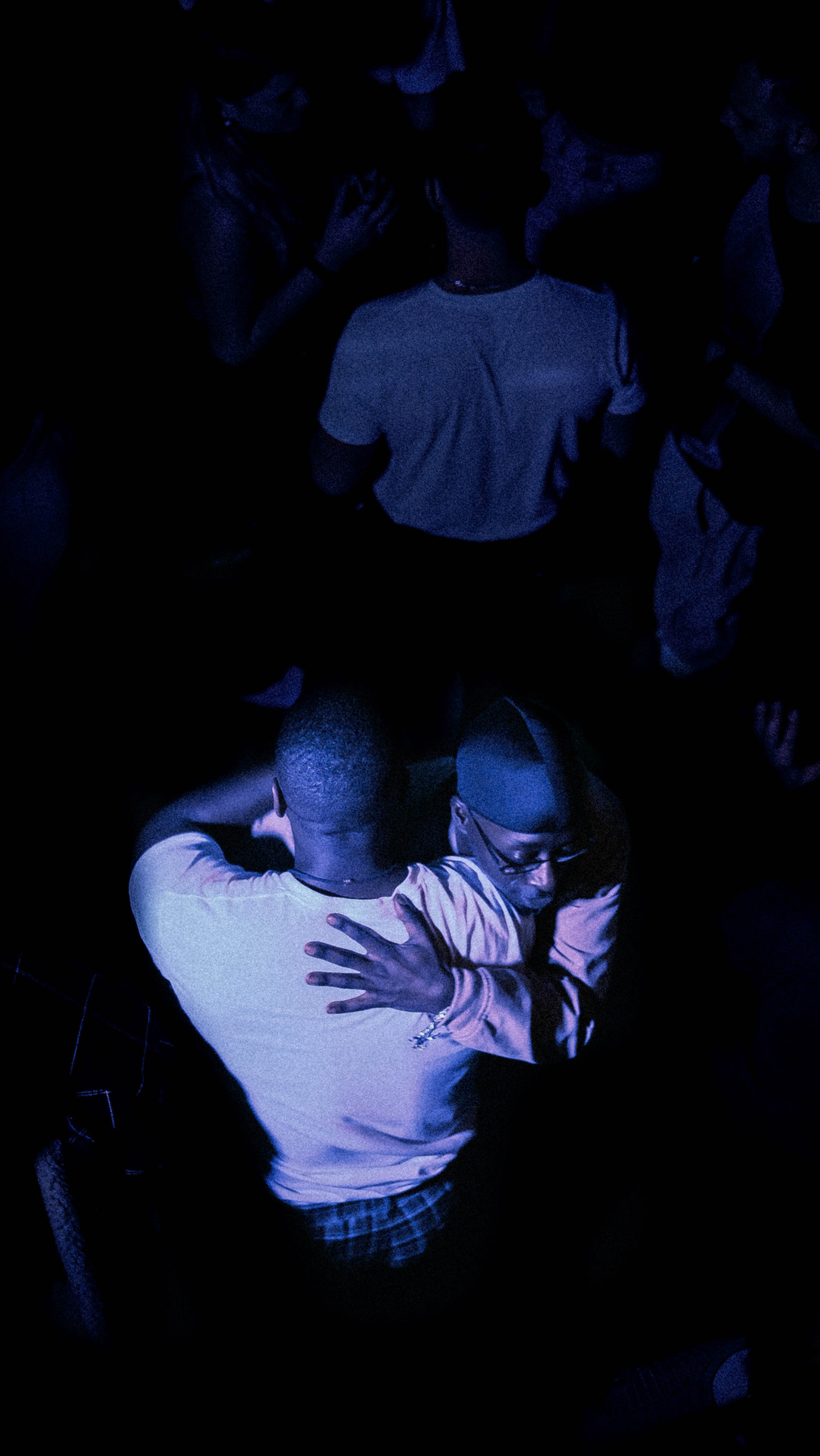 An image of two Black males dancing with each other while embracing in a club.