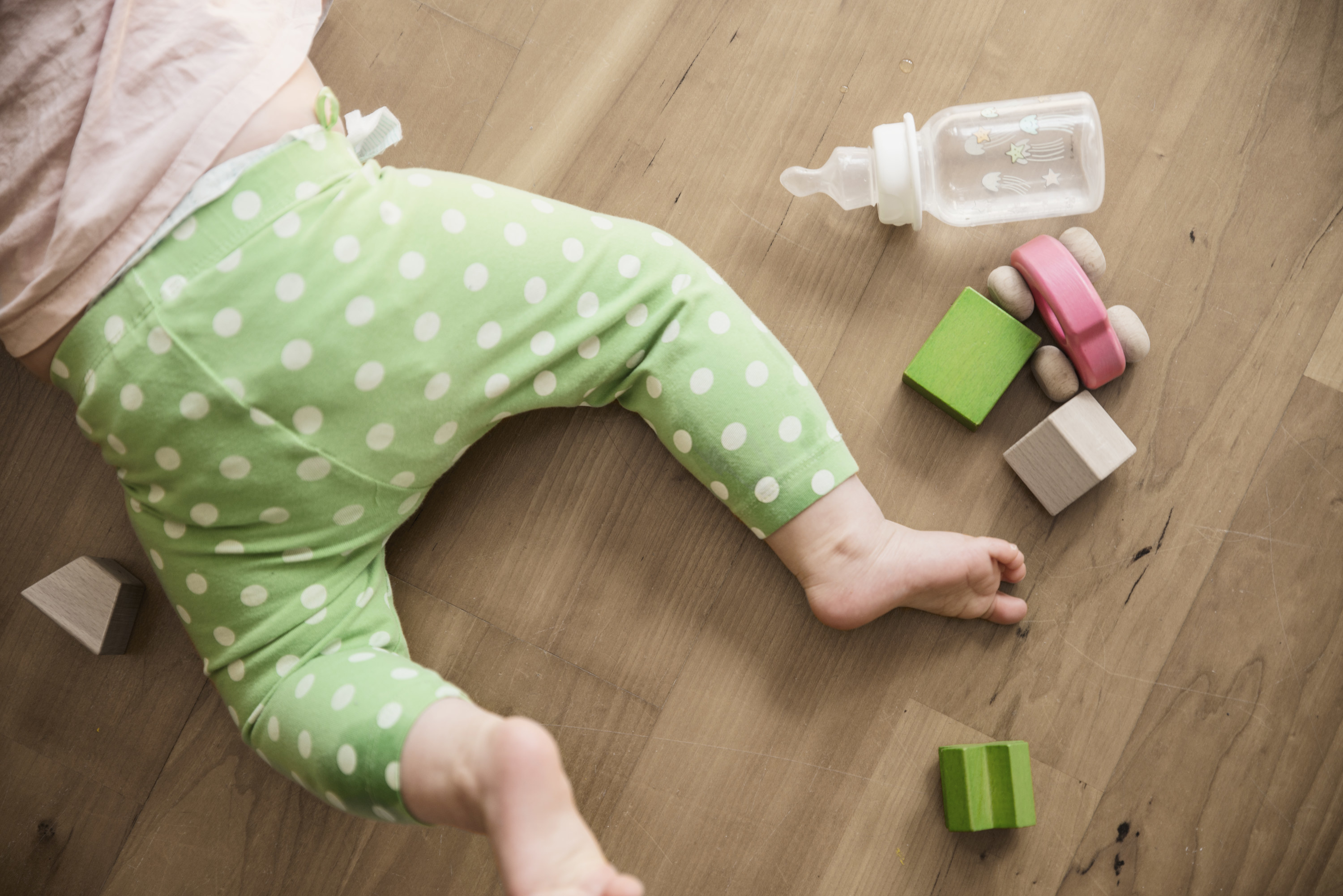 a baby on the floor with blocks and baby bottle