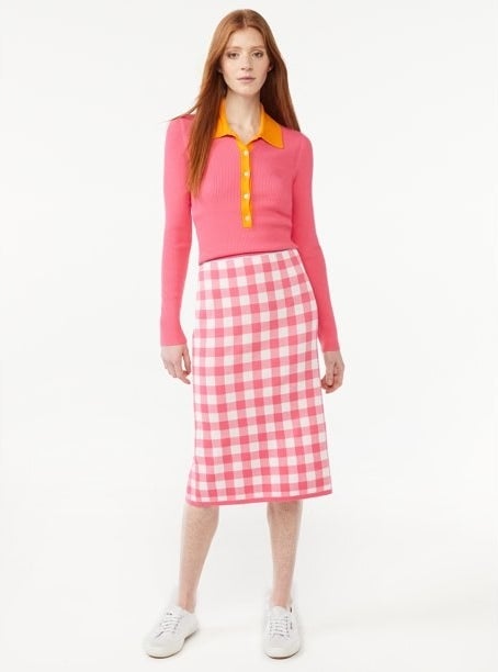 Model wearing pink and orange top with pink and white skirt with white shoes