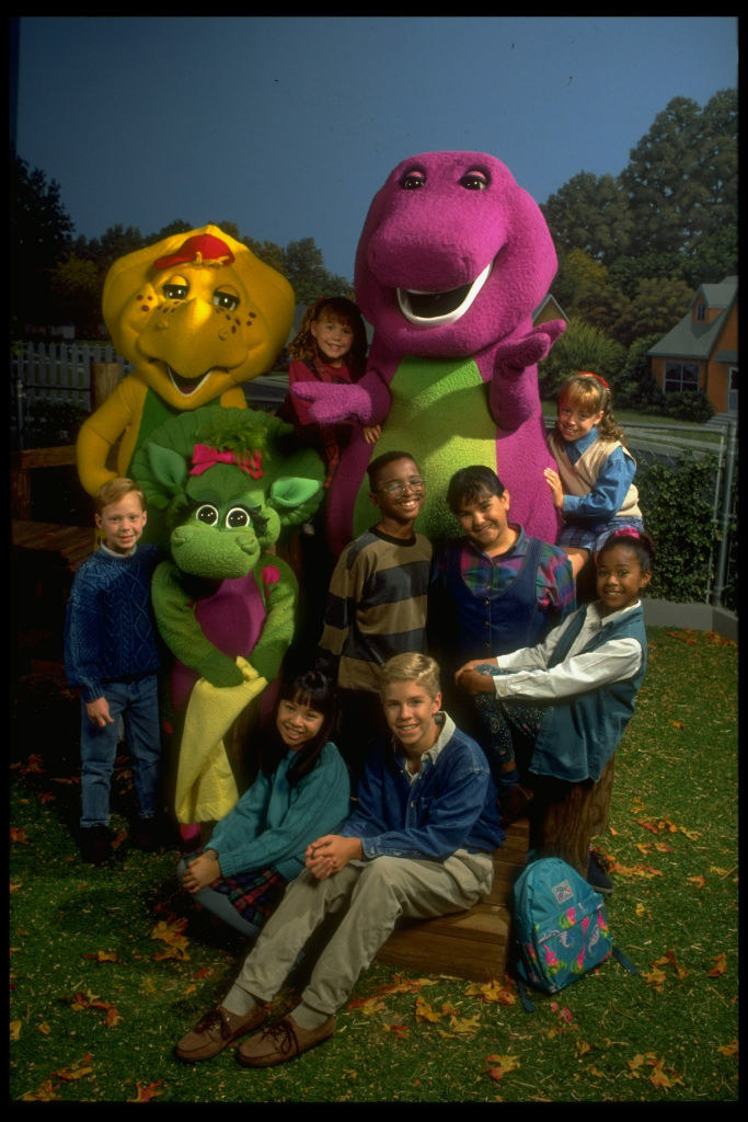 Barney and his friends pose for a group photo on the playground with leaves on the ground