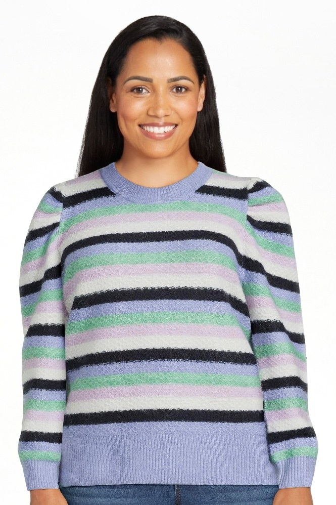 Model wearing purple, blue, green, black and white sweater with jeans