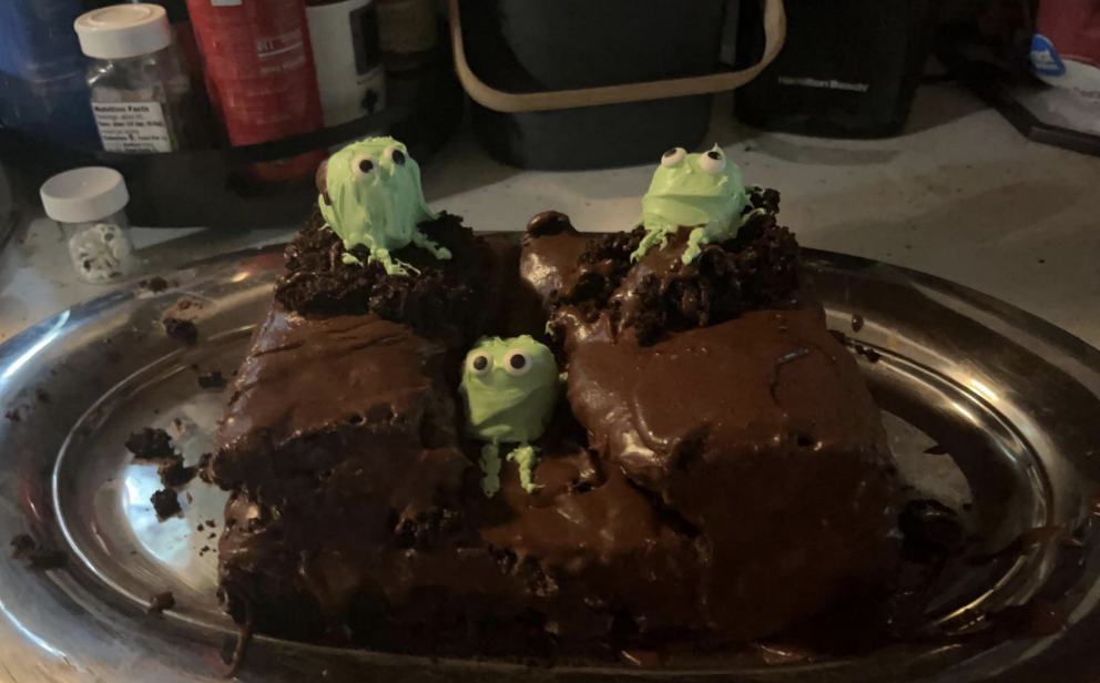 A chocolate cake with green frogs in it