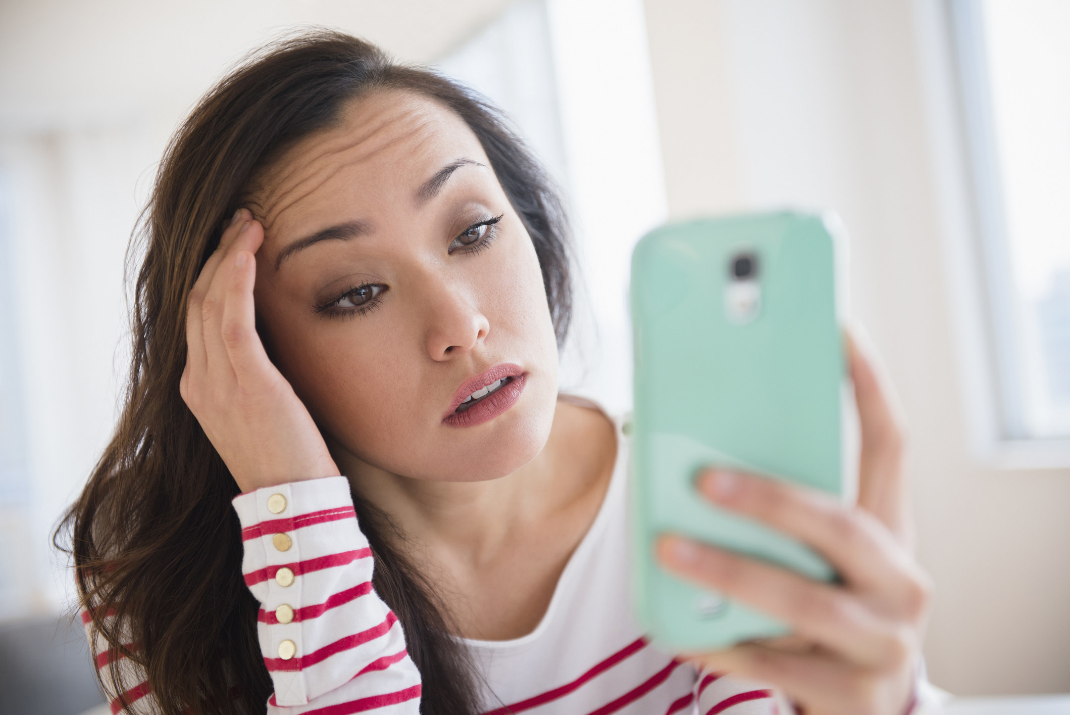 Woman looking at her phone and looking tired