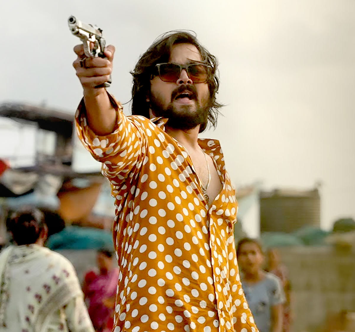 Bhuvan, wearing sunglasses, points a gun at someone