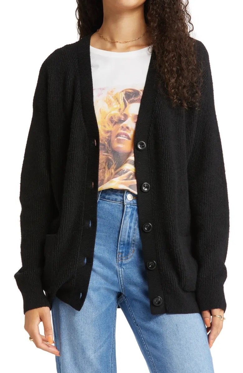 Model wearing black sweater with jeans and a graphic tee