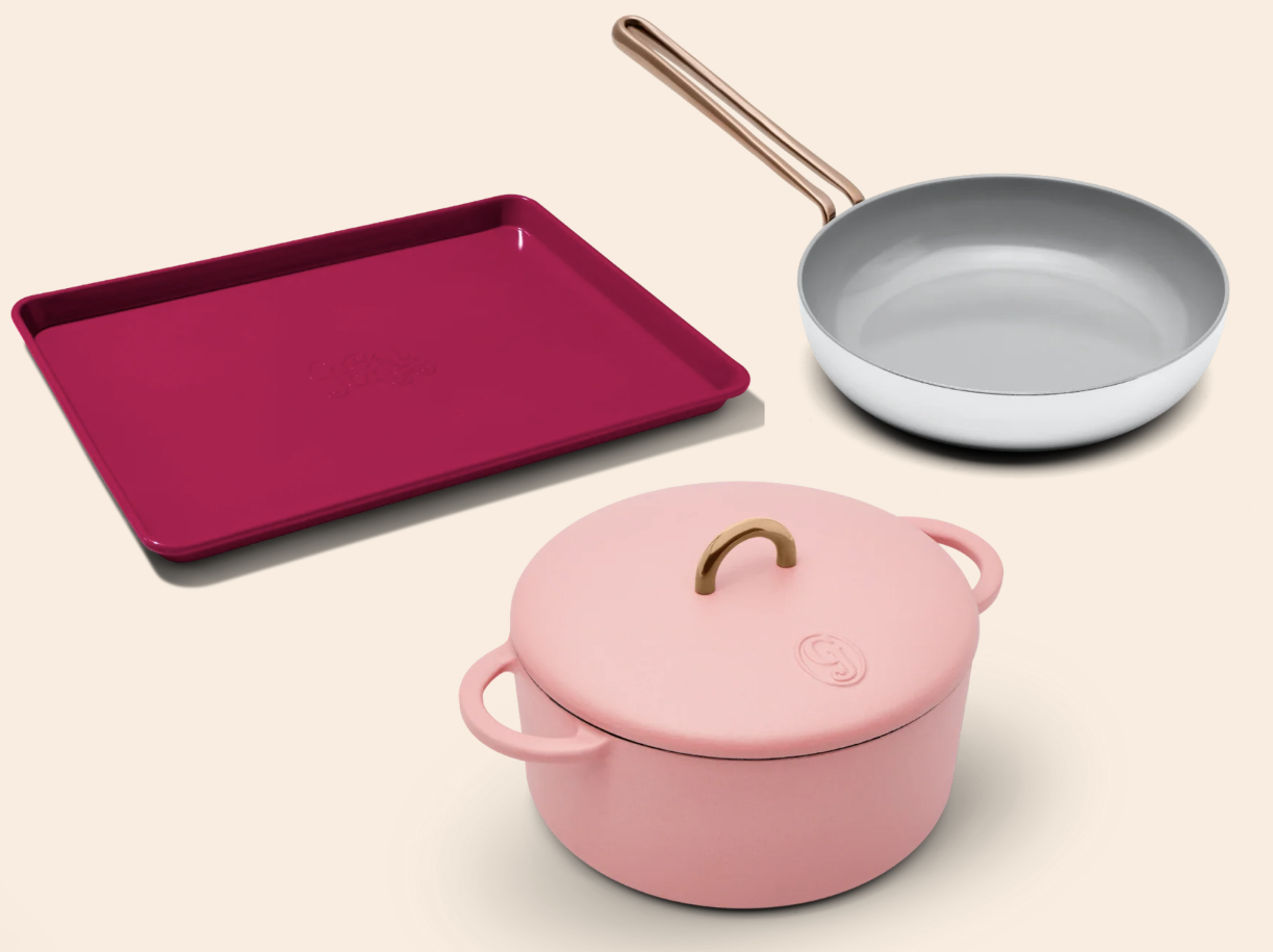 a cookware set featuring a maroon sheet tray, pink Dutch oven, and metal frying pan
