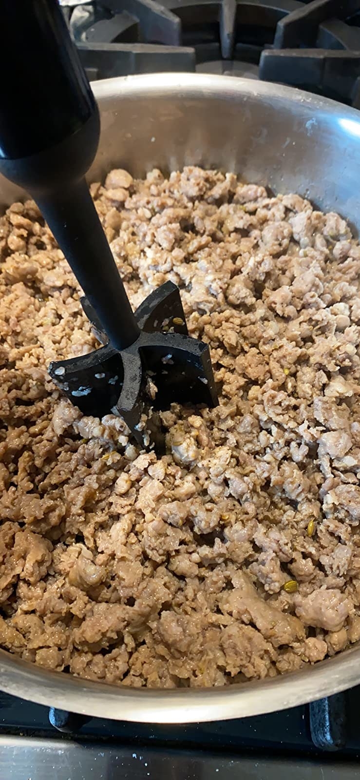 Reviewer&#x27;s photo of the masher breaking up ground meat in a pan