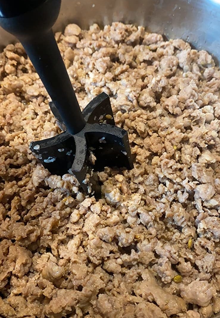 Reviewer&#x27;s photo of the masher breaking up ground meat in a pan