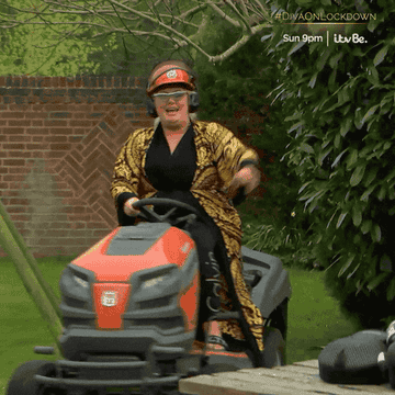 a woman in a bathrobe driving a lawmower in a backyard