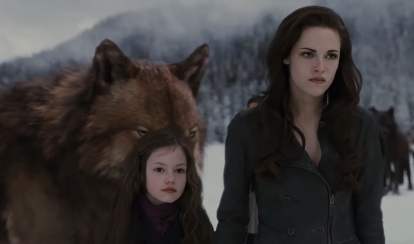 MacKenzie standing next to Kristen Stewart in the woods with wolves behind them