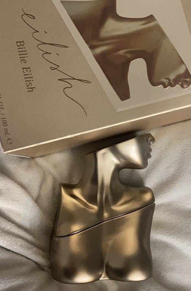 bottle of Eilish perfume on a bed next to packaging